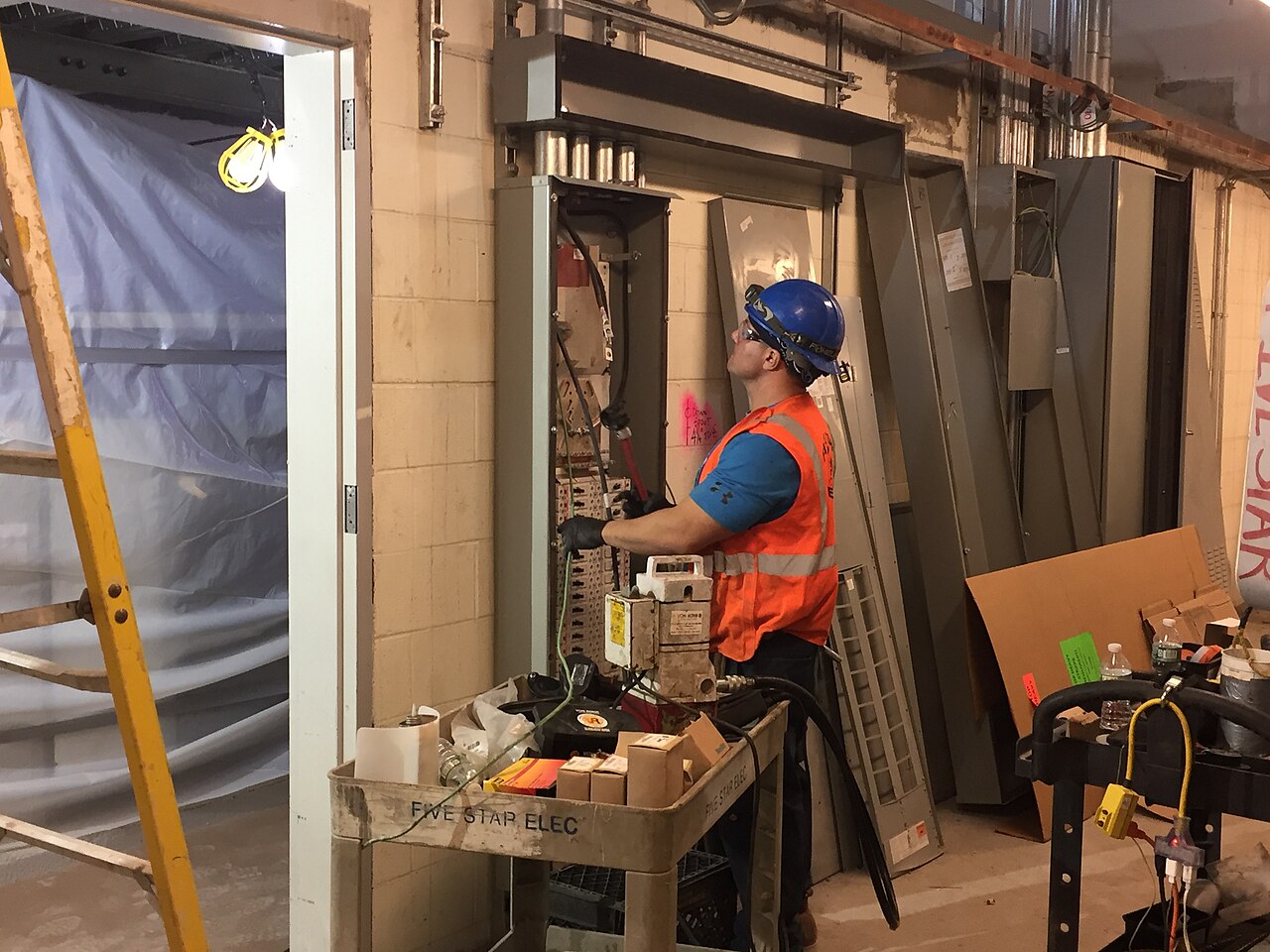 Electrician pulling wire near an electrical panel